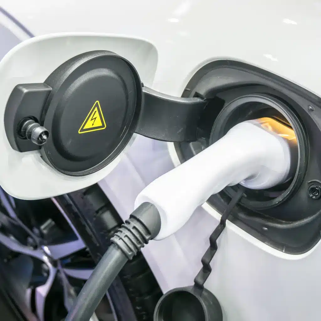 Recharge voiture électrique : branchement et sécurité de la prise. Recharge de voiture électrique. Le connecteur est branché dans la prise. Symbole d'avertissement haute tension (éclair jaune) sur le couvercle.